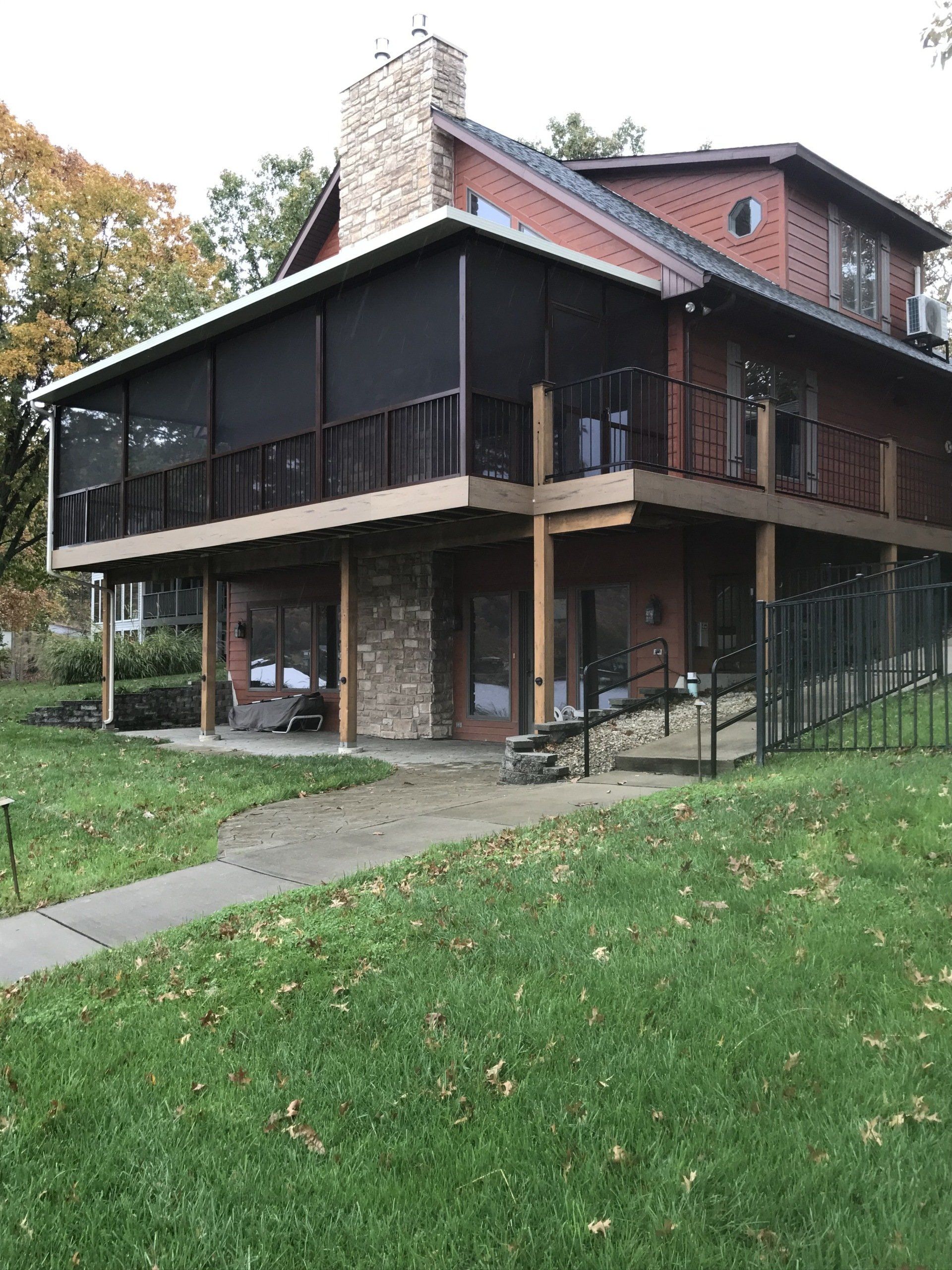 Two-story house with a screened porch, brick chimney, and grassy yard