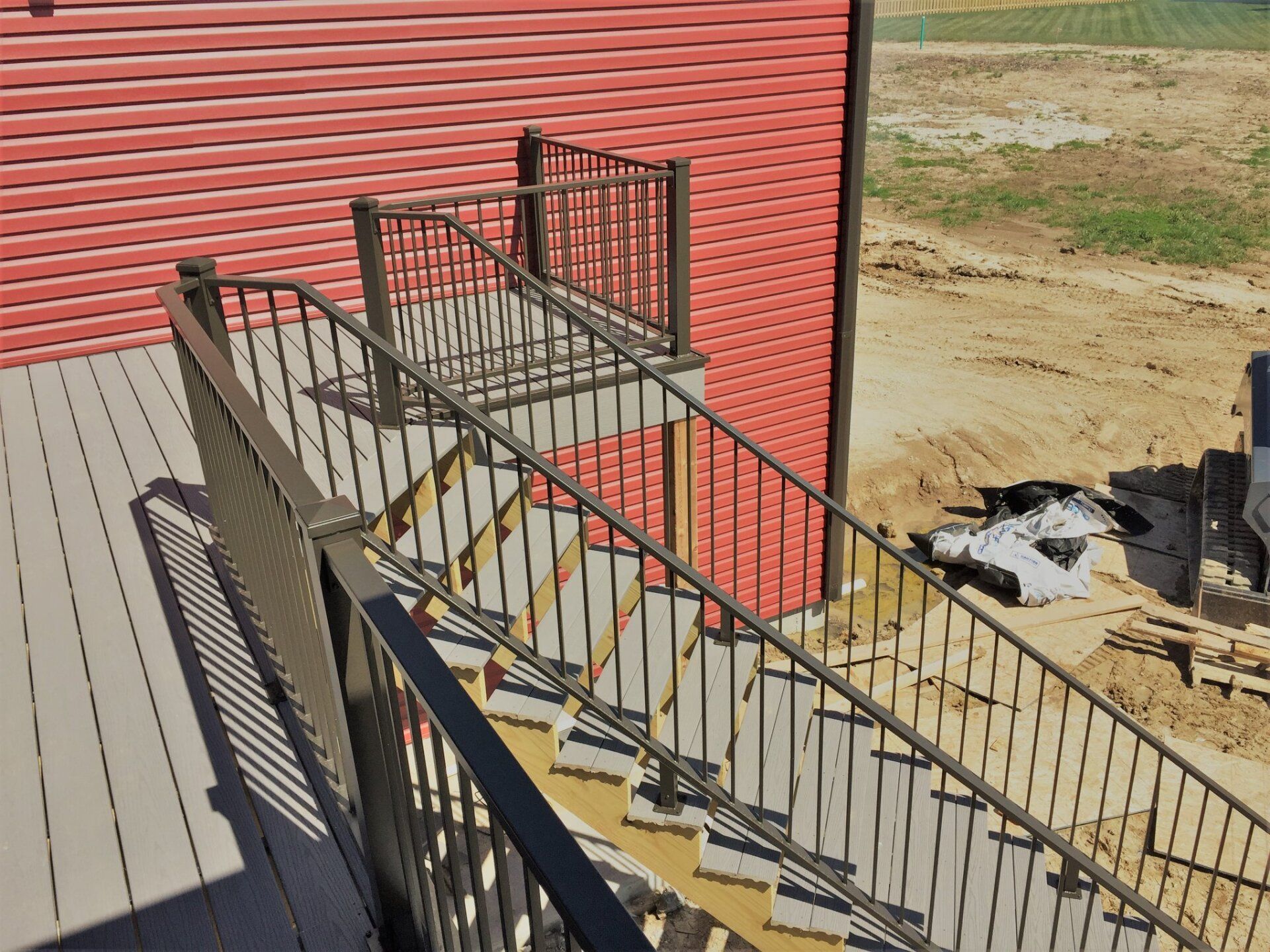 Outdoor wheelchair ramp with metal railings beside a red building, under construction