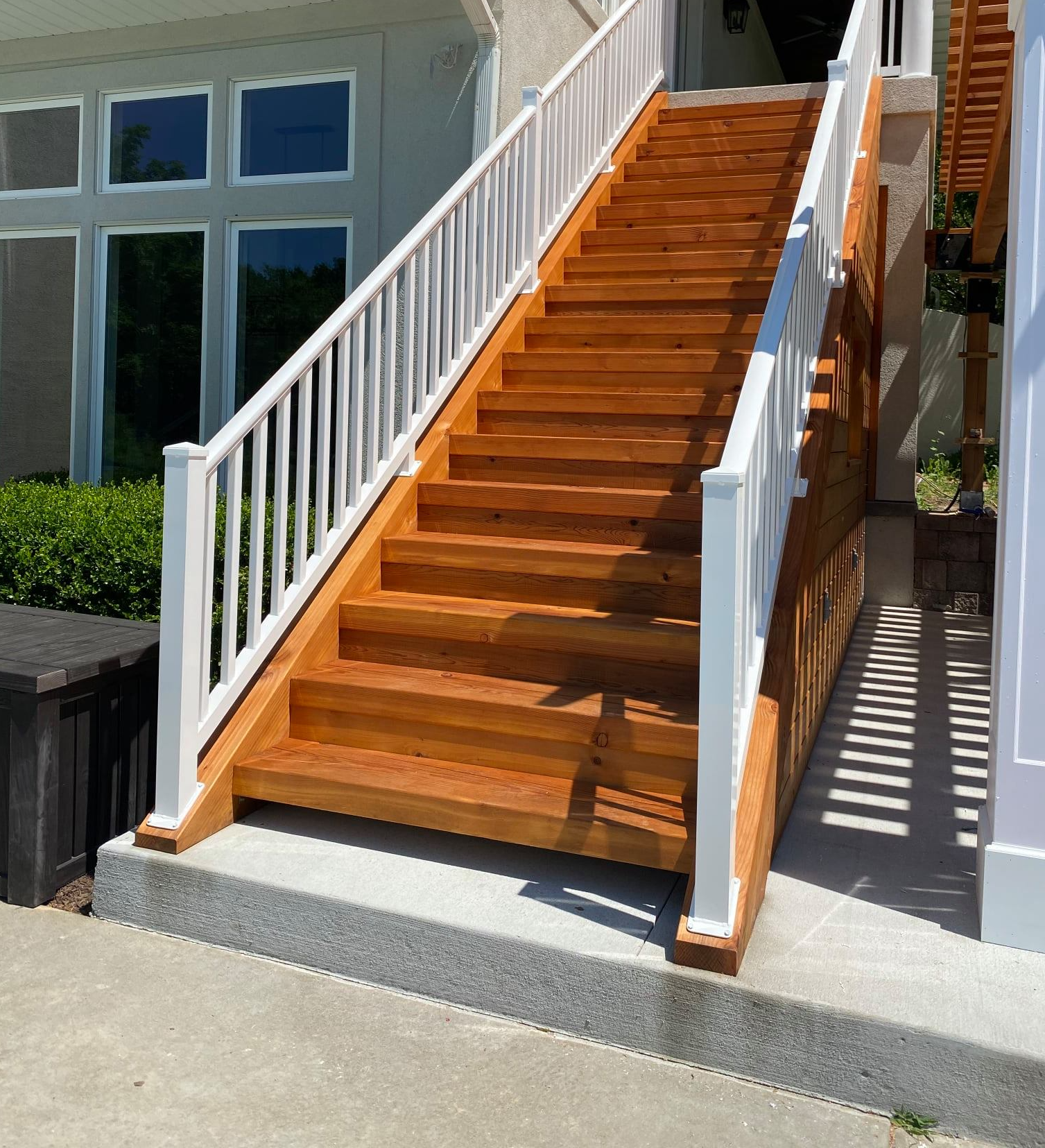 Wooden outdoor staircase with white railings leading up to a house entrance