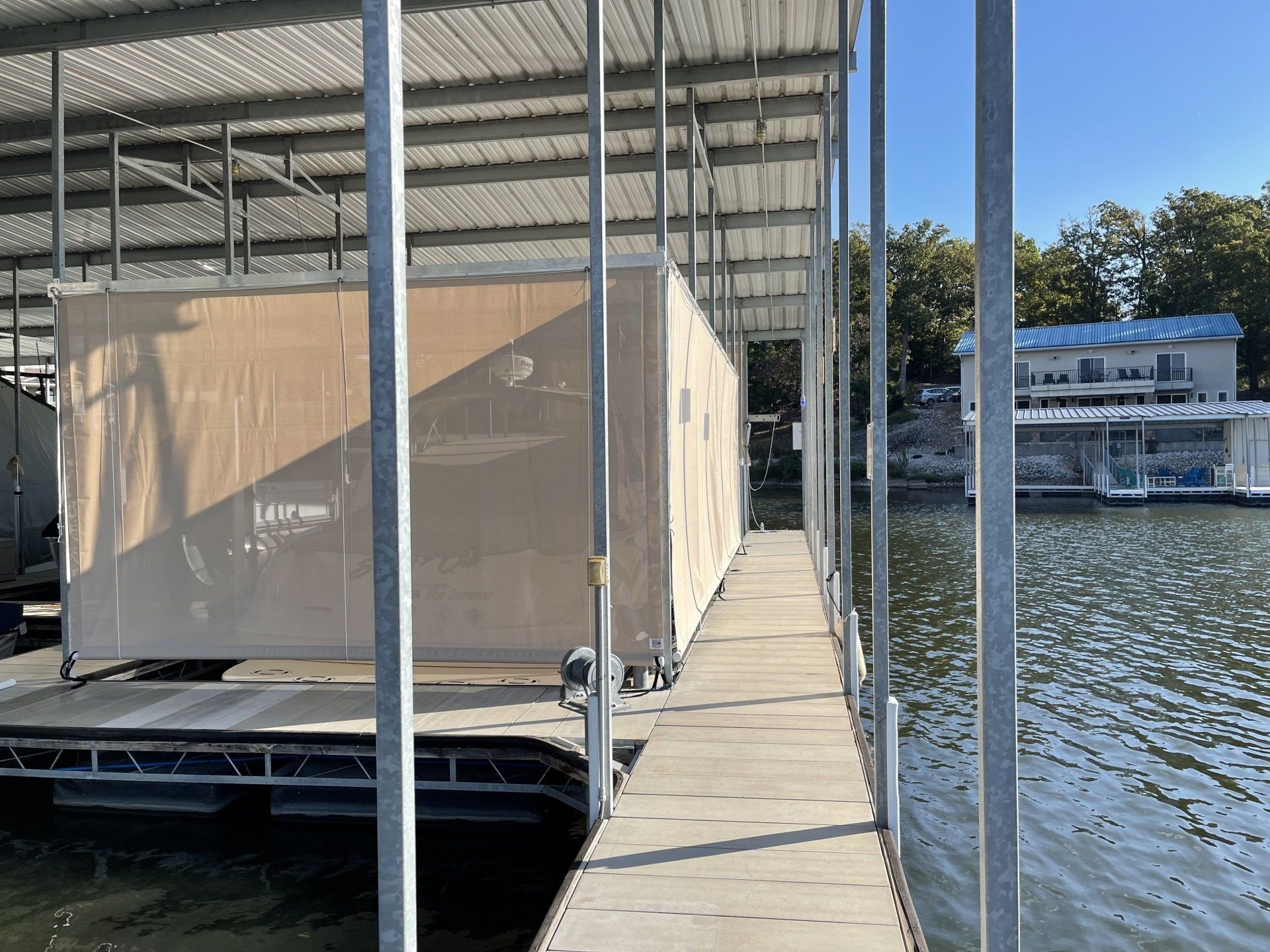 Covered dock walkway beside a large wrapped shipment floating on the water