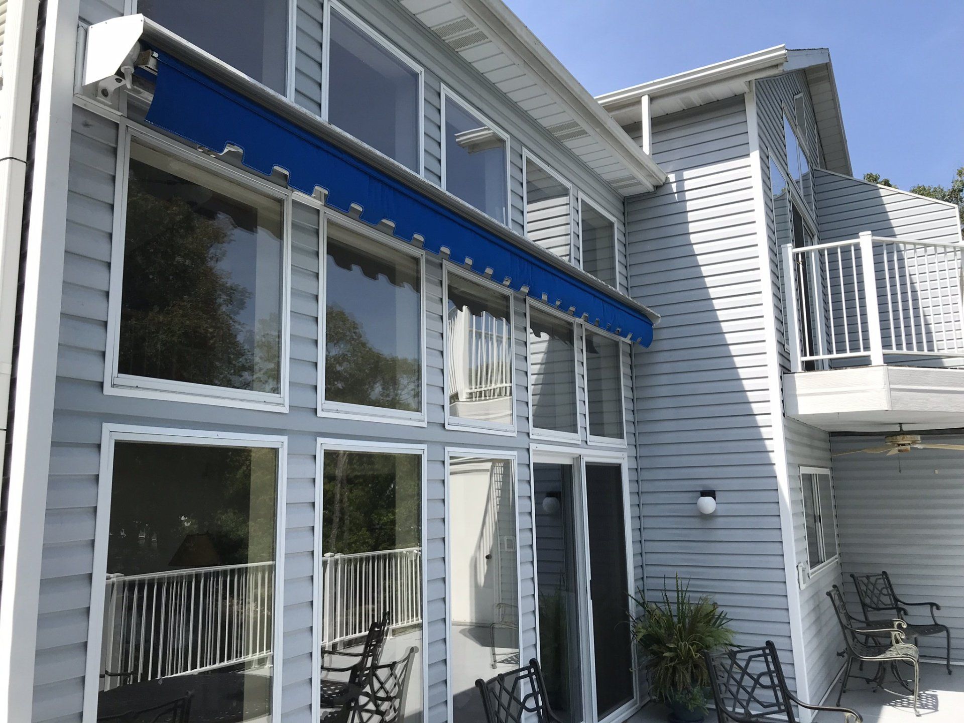 Blue-awning patio with large windows and a white house exterior