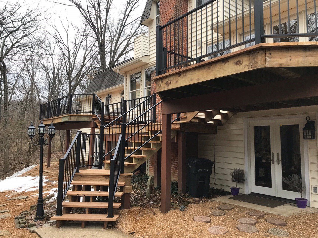 Exterior of a townhouse with black staircases, balconies, and snow on the ground, viewed from the side