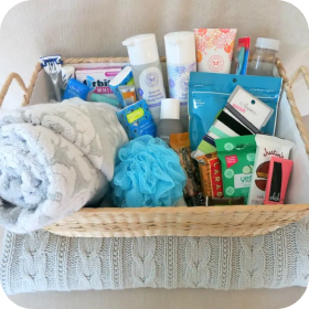 Wicker basket filled with toiletries, cleaning supplies, and folded towels on a lace-covered surface
