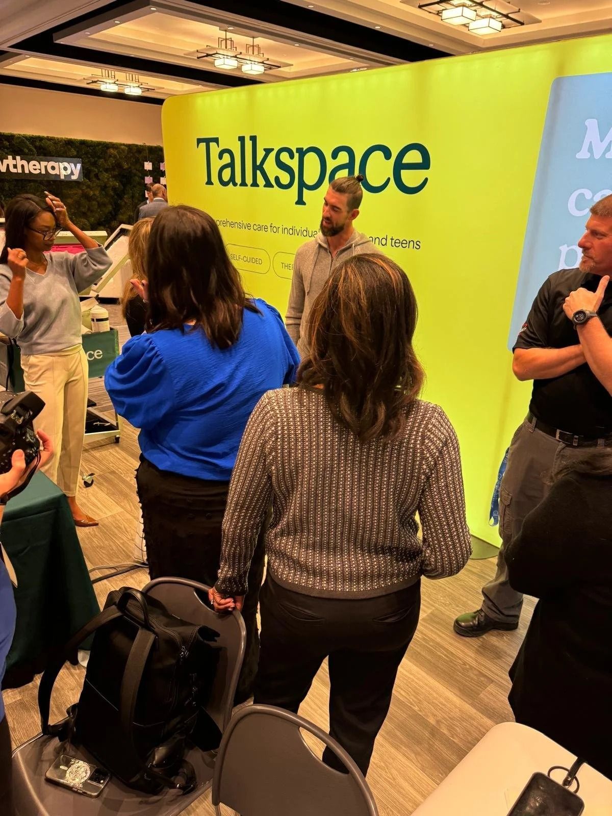 Talkspace booth at a conference with a presenter and attendees listening