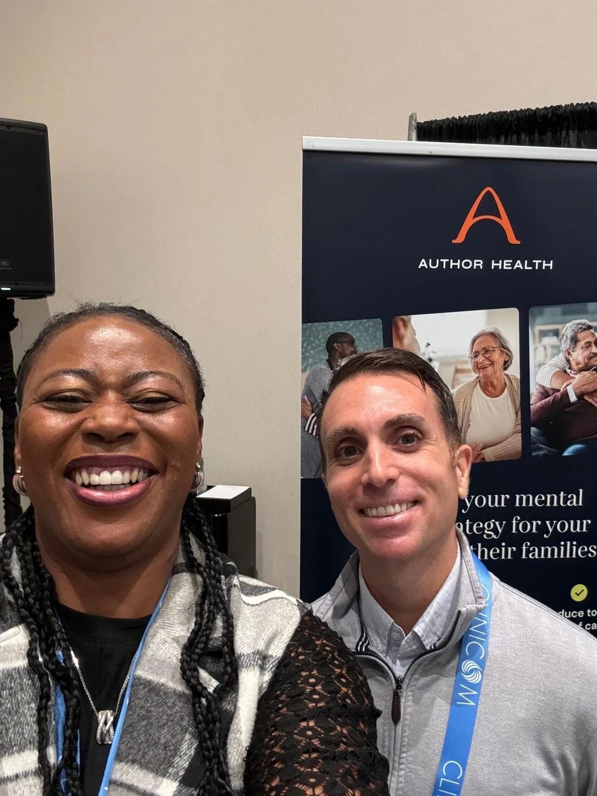 Two smiling people pose at a conference booth with an Author Health banner in the background