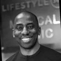 Smiling man in black shirt in front of a blurred event backdrop