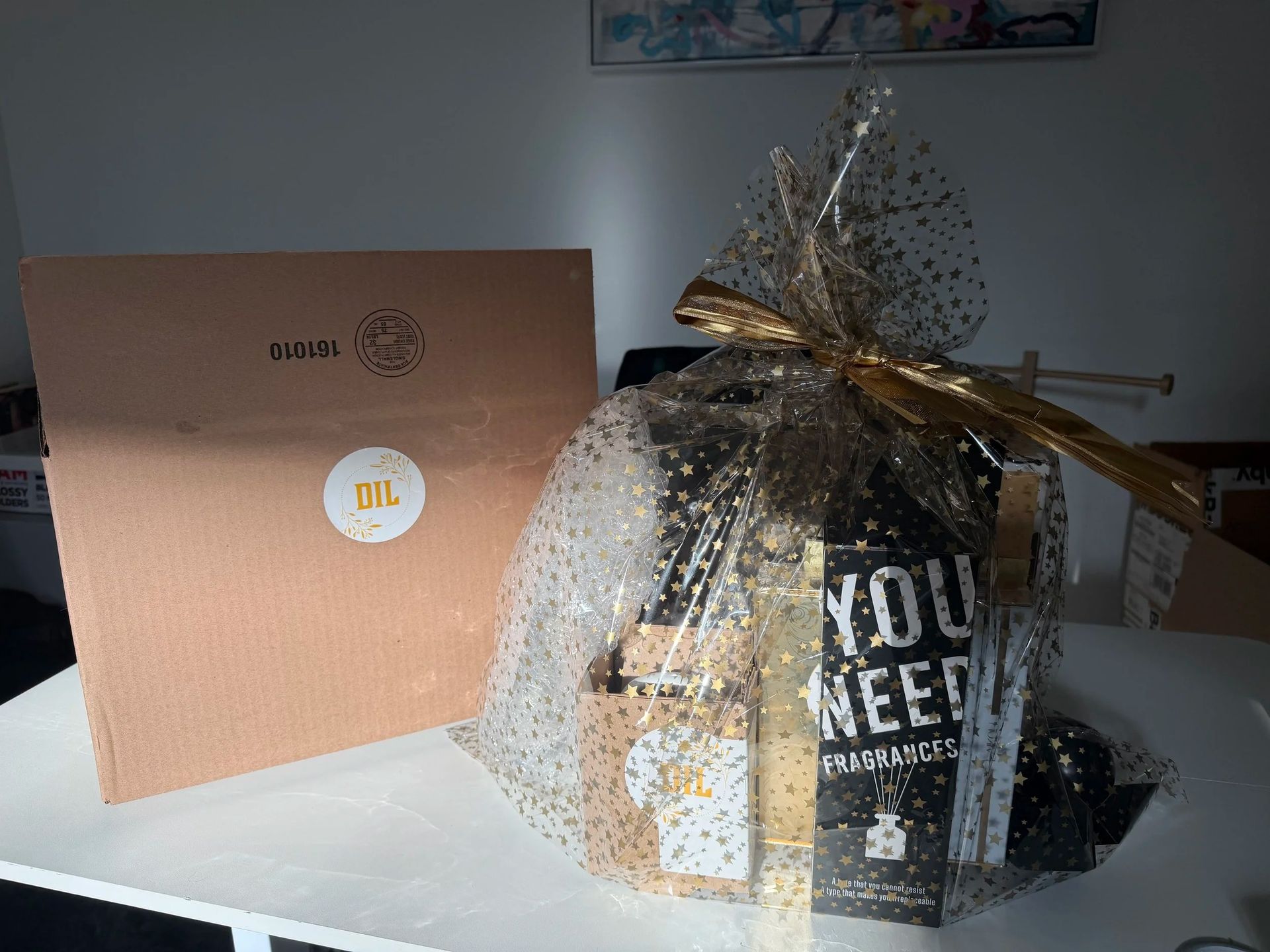Gift basket with popcorn and snacks beside a pink OIAL box on a white table.