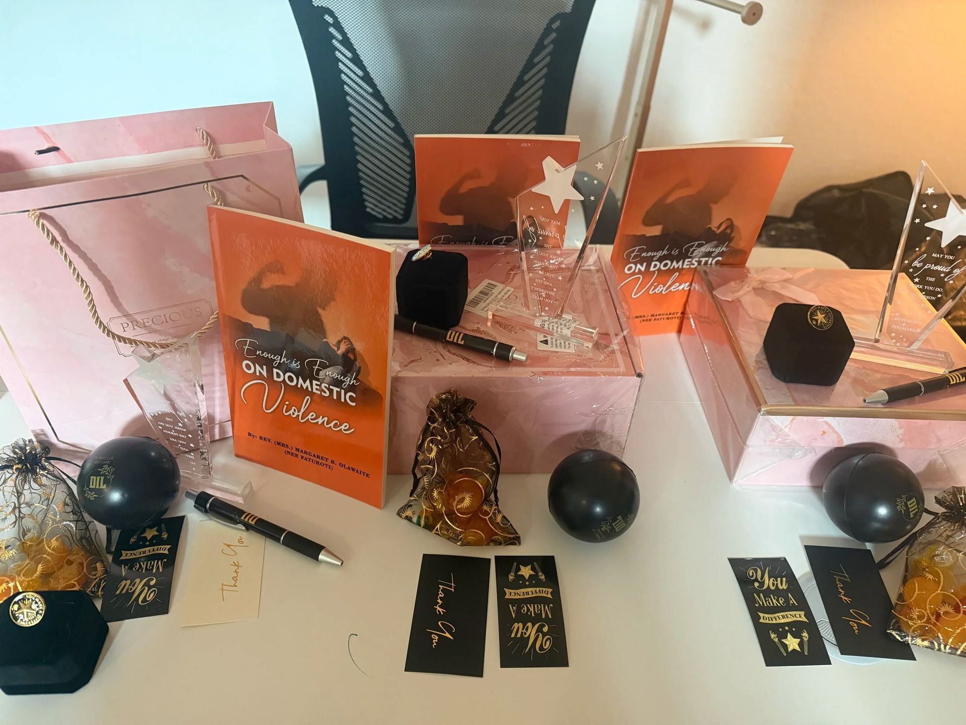 Pink and orange cosmetic gift boxes arranged with black ornaments and gold accents on a table