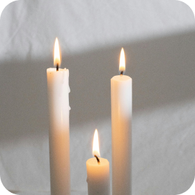 Three lit white candles against a soft gray background