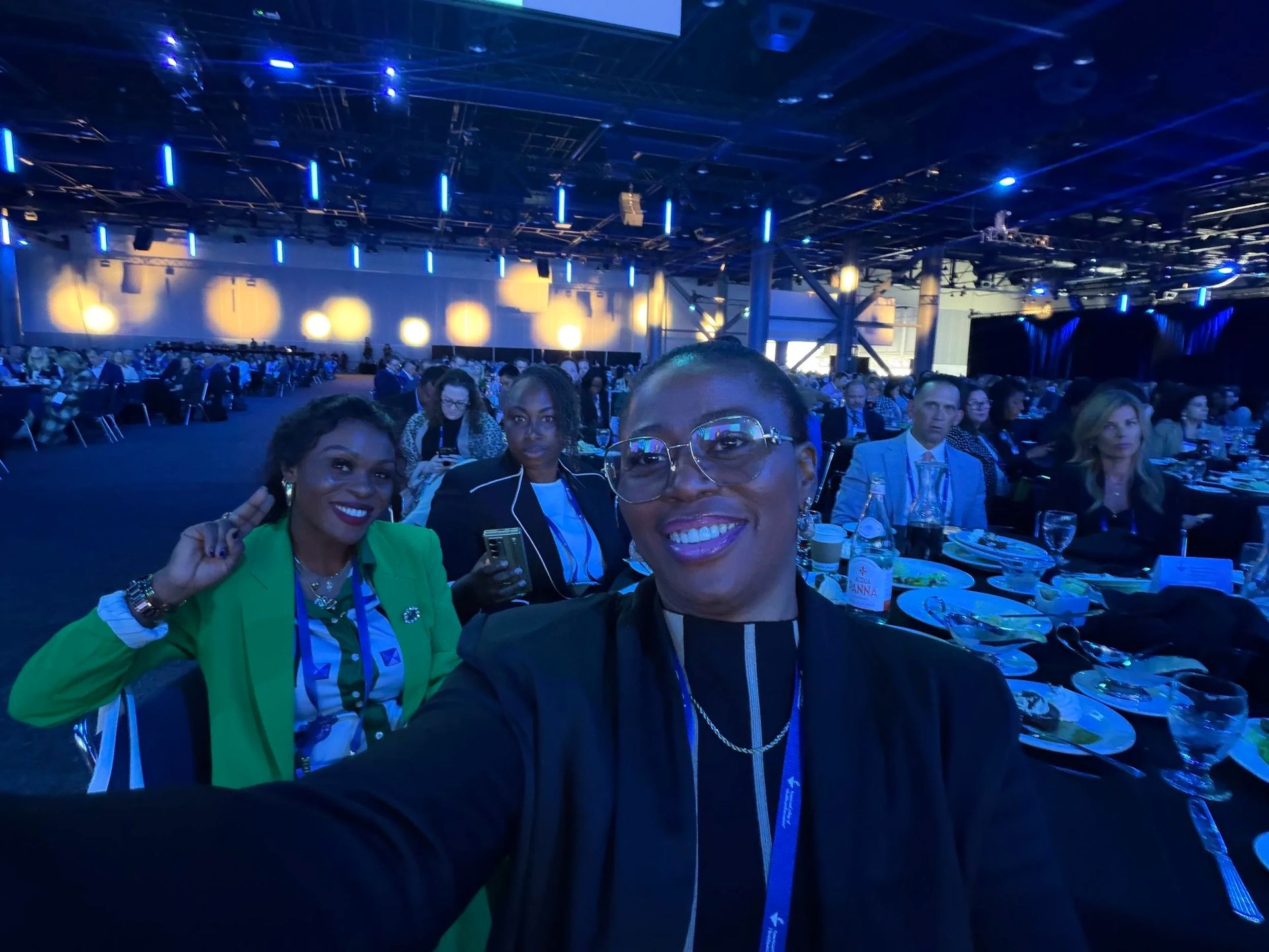 Selfie at a lively blue-lit event with people seated at tables in the background