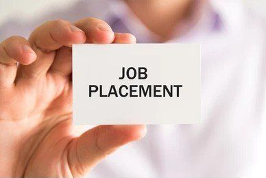 Hand holding a card reading “JOB PLACEMENT” against a blurred background