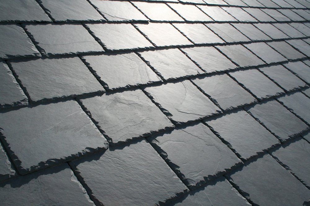 Slate Roof — Gregory, TX — Berryman Roofing Wet gray stone pavement with rectangular tiles and a bright reflection of light
