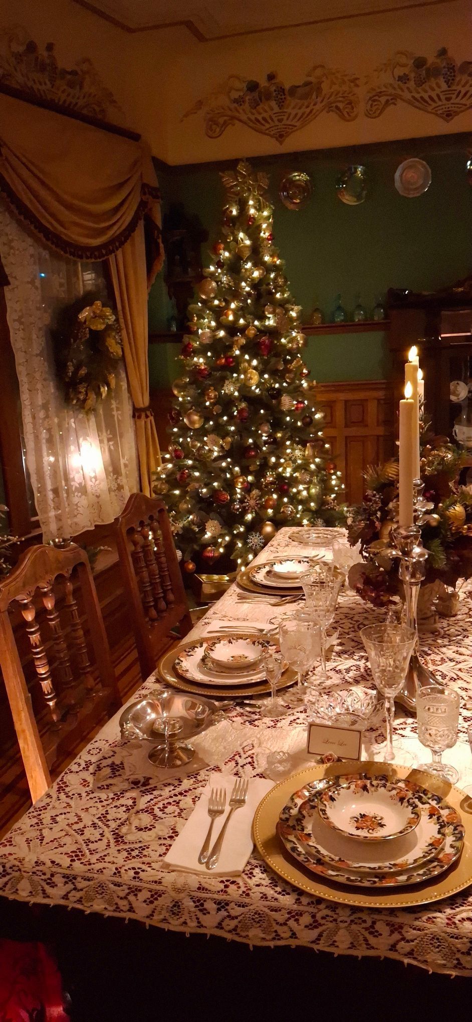 Christmas dinner table set with a decorated tree in the background.