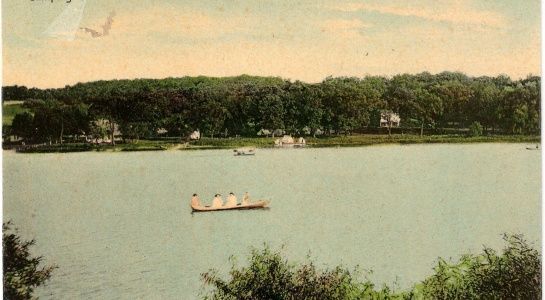 Lake scene with rowboat, trees along shore.