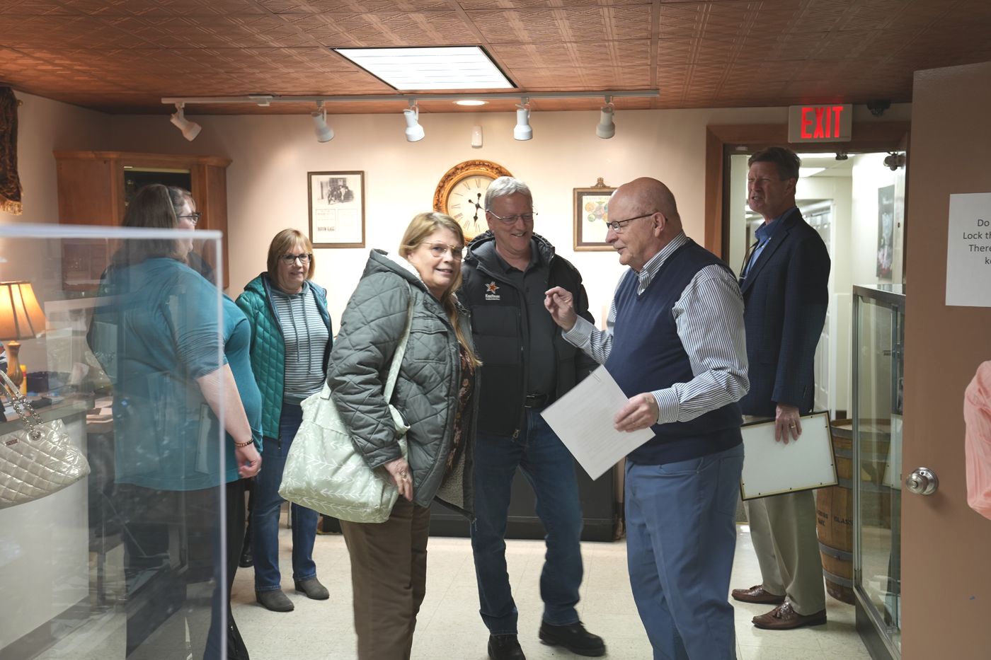 People talking inside a room with display cases. One man gestures while holding papers.