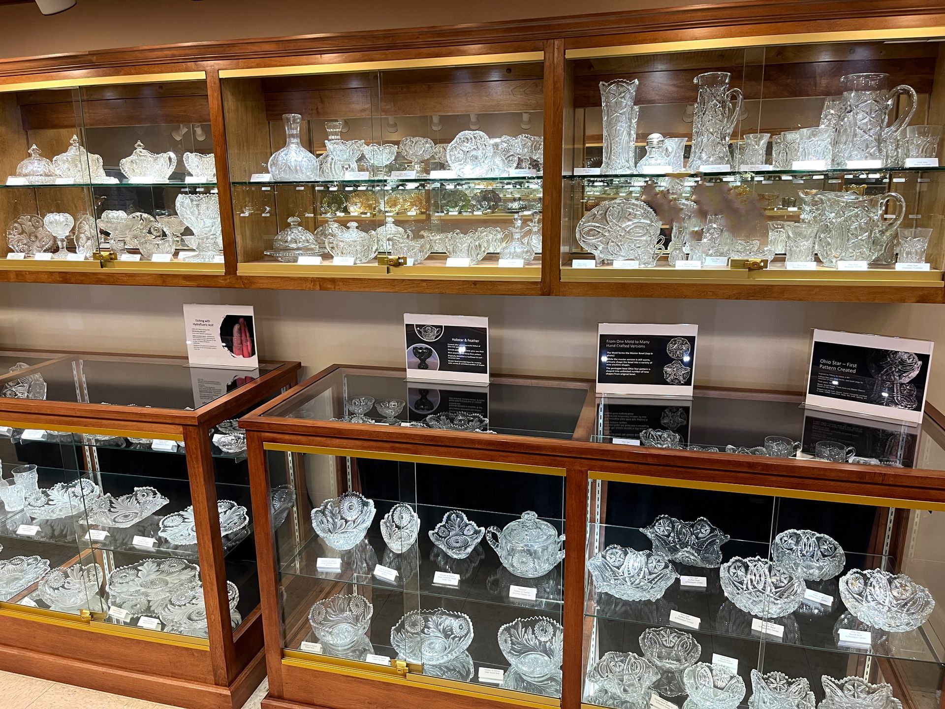 Crystal glassware displayed in lit glass cabinets inside a store.