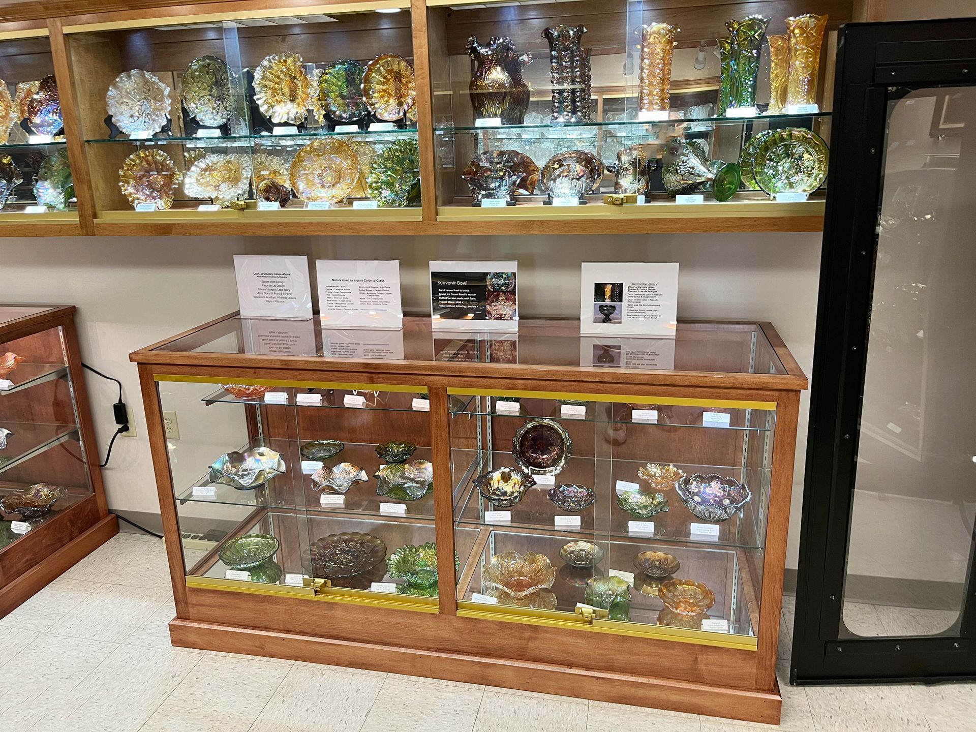 A display case with glass shelves showcasing colorful, decorative objects; a shop setting.