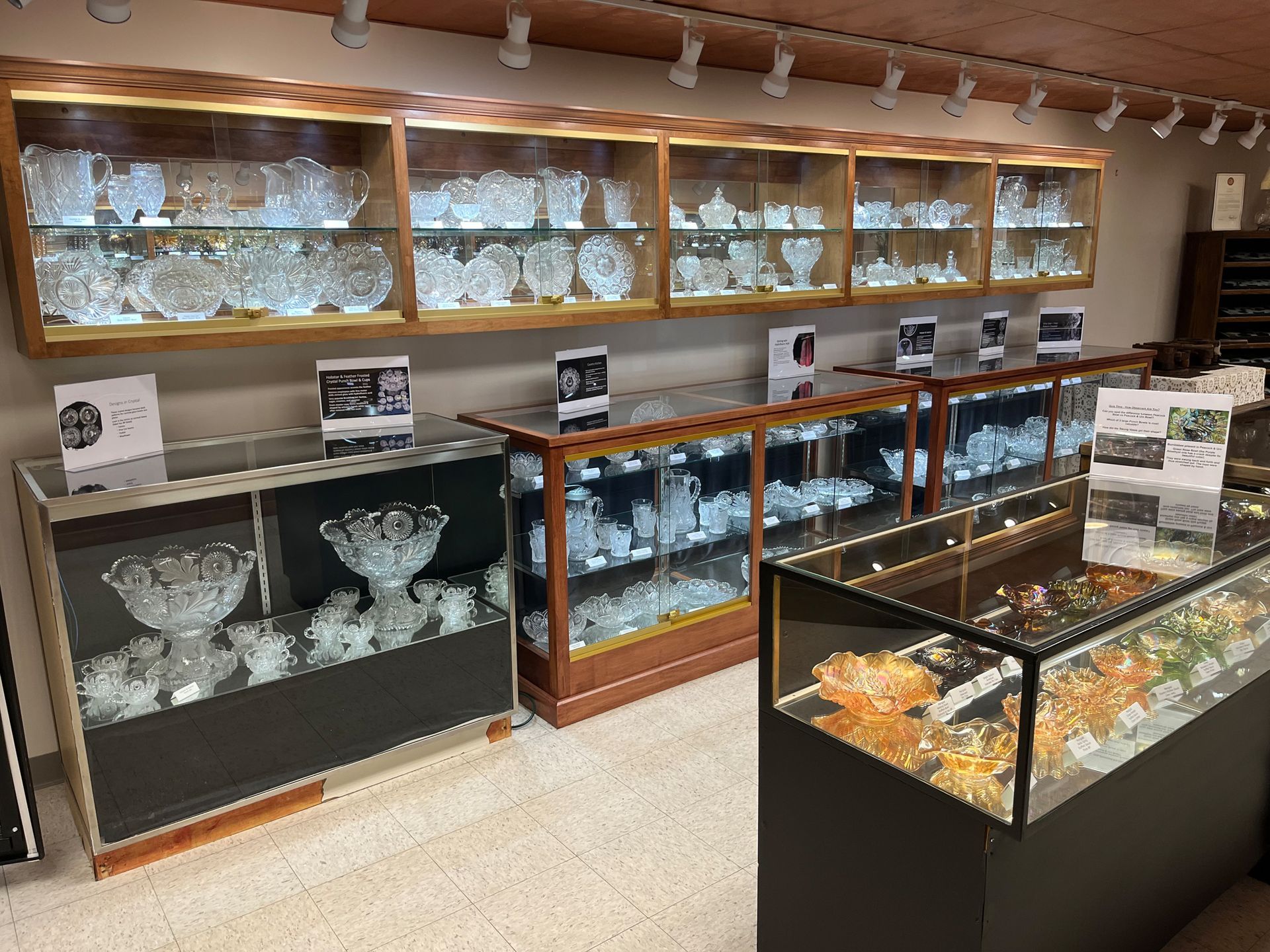 Crystal glassware displayed in lit glass cases within a store.