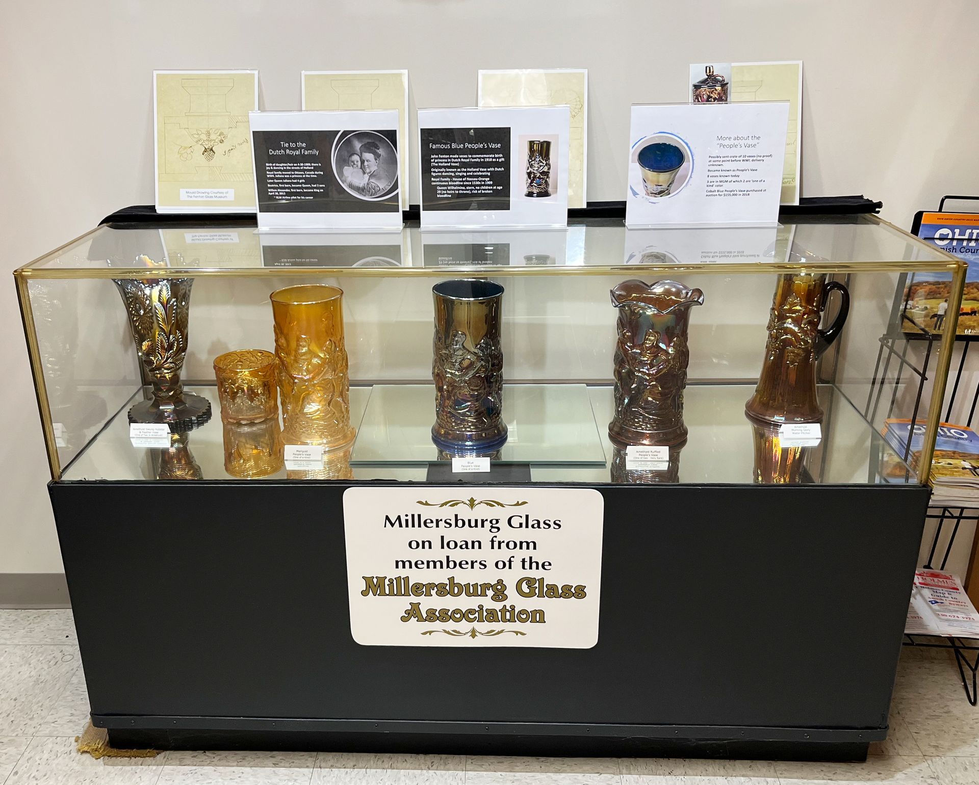 Display case with colorful glass vases; signs about the items.