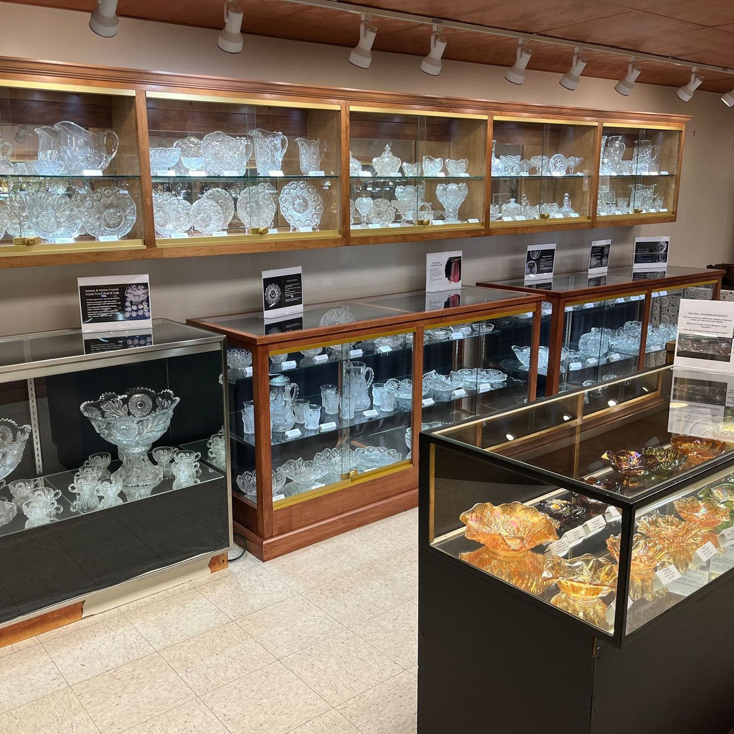 Crystal glassware displayed in lit cabinets and glass display cases in a store.