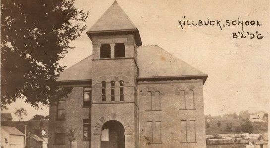 Killbuck School building in sepia tone. Brick structure with tower, archway entrance.