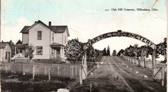 Oak Hill Cemetery entrance in Miamisburg, Ohio. A house is to the left. A long driveway leads towards the cemetery.