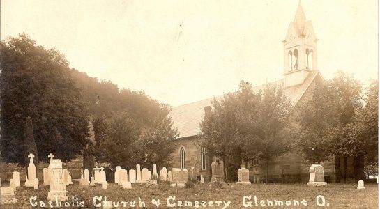 Catholic church with cemetery in Glenmont, Ohio. Sepia-toned photo of church with spire and gravestones.