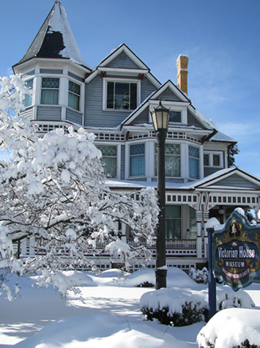 Victorian house covered in snow, sign reads 