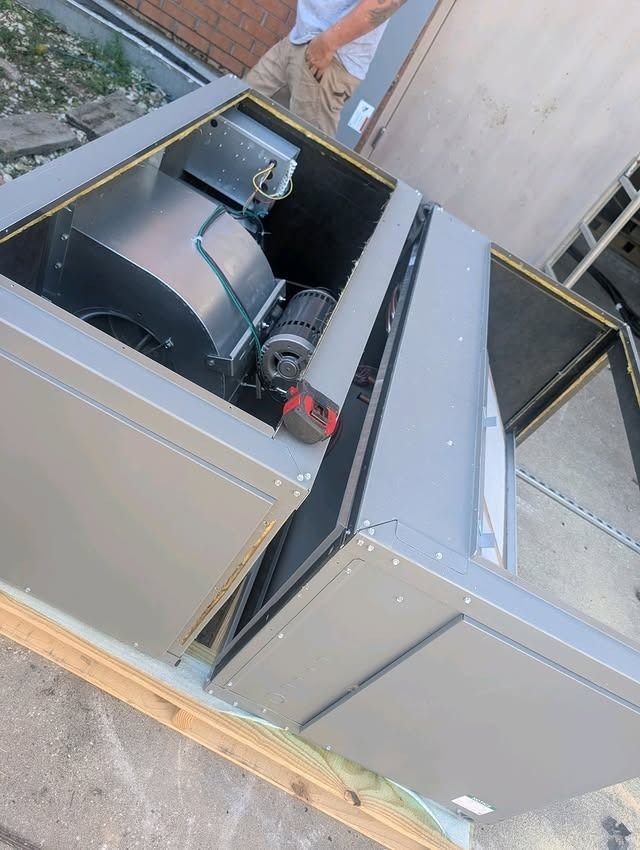 Open metal HVAC unit on a rooftop, showing internal fan and ductwork.