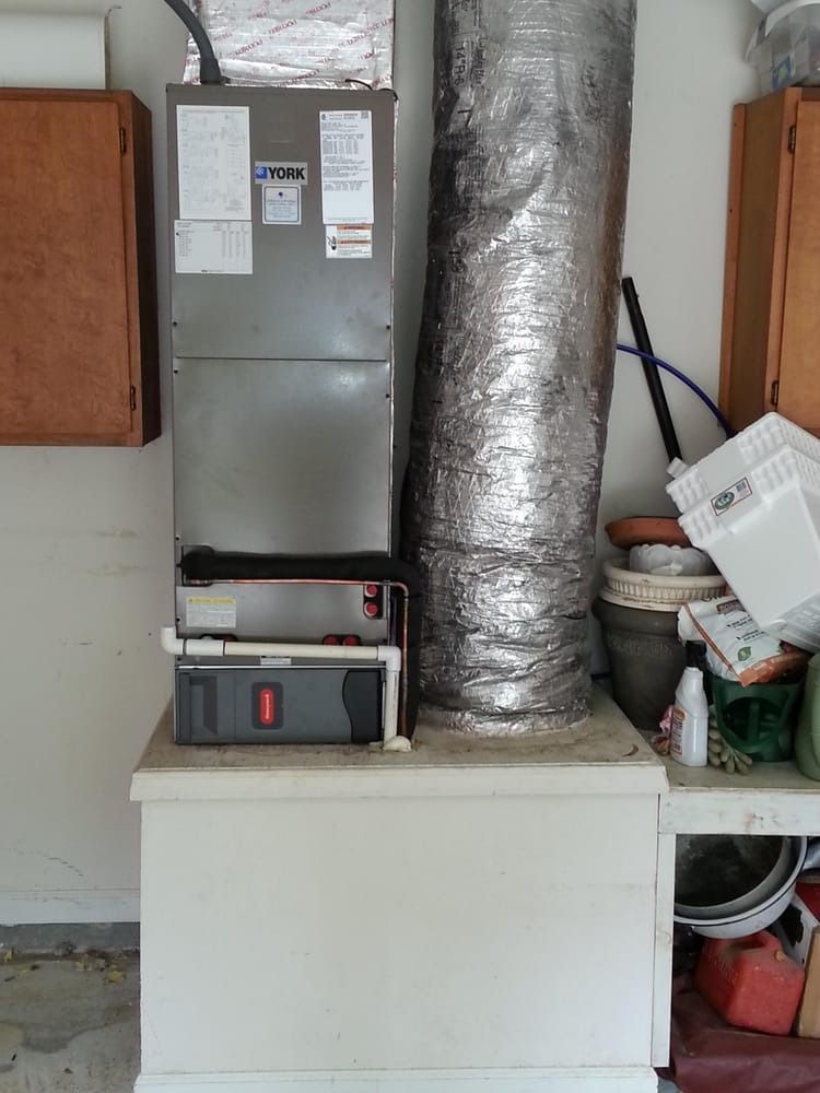 Basement utility area with furnace, ductwork, and storage items on a white platform.