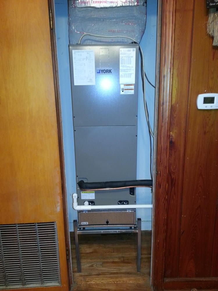 Gray utility cabinet in a narrow doorway, with vents, papers, and cables in a wooden hallway.