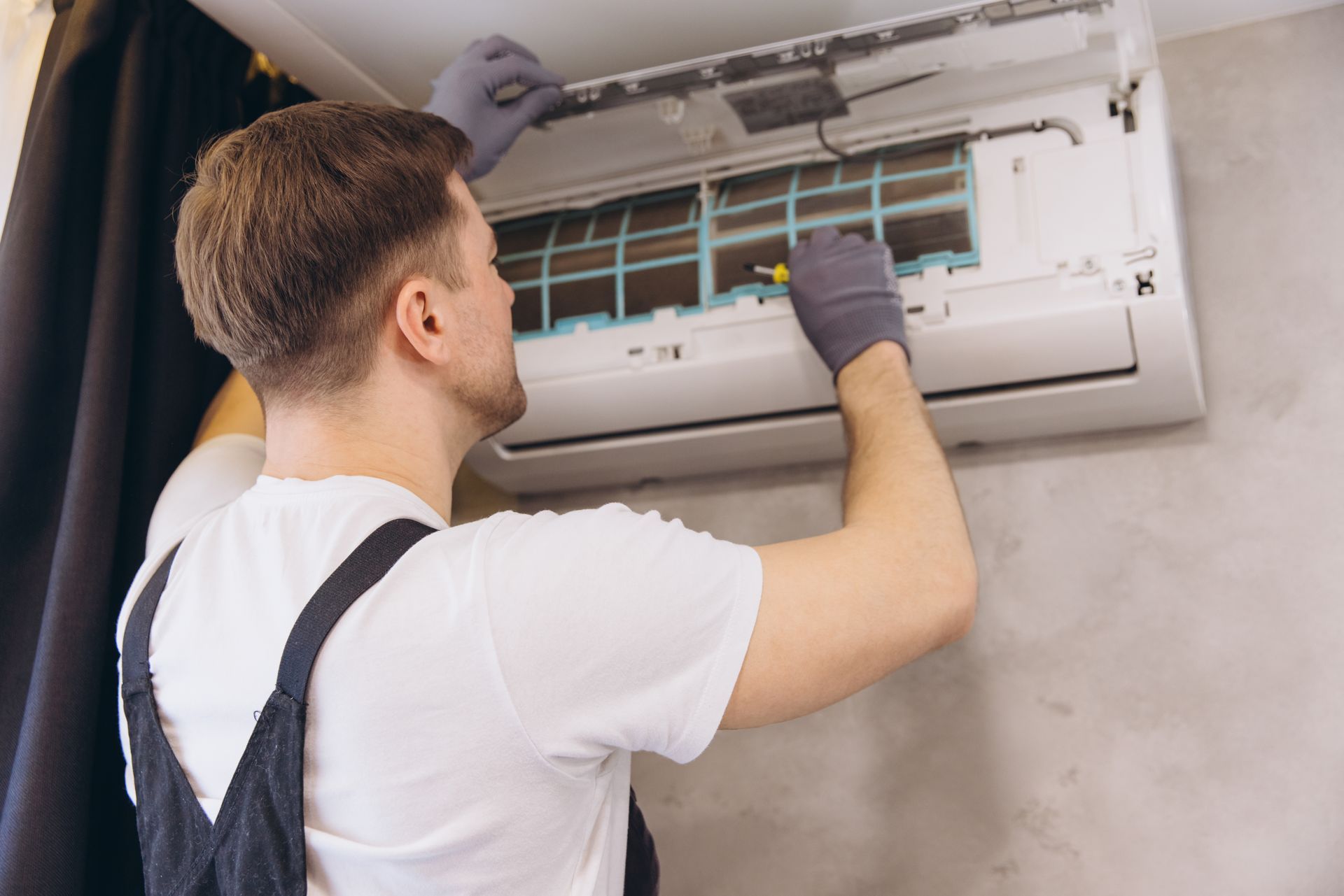 Technician repairing a wall-mounted air conditioner with the cover open