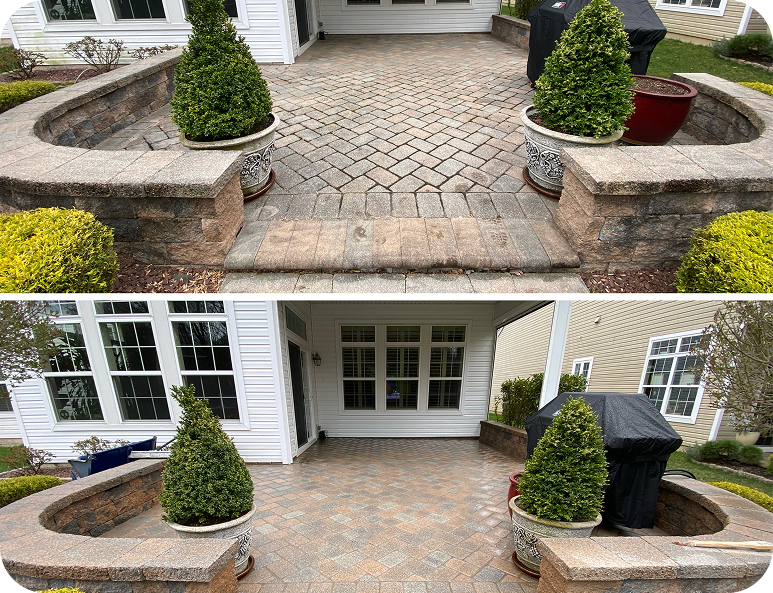 Front entry patio with stone planters, shrubs, and a cobblestone walkway leading to white double doors.