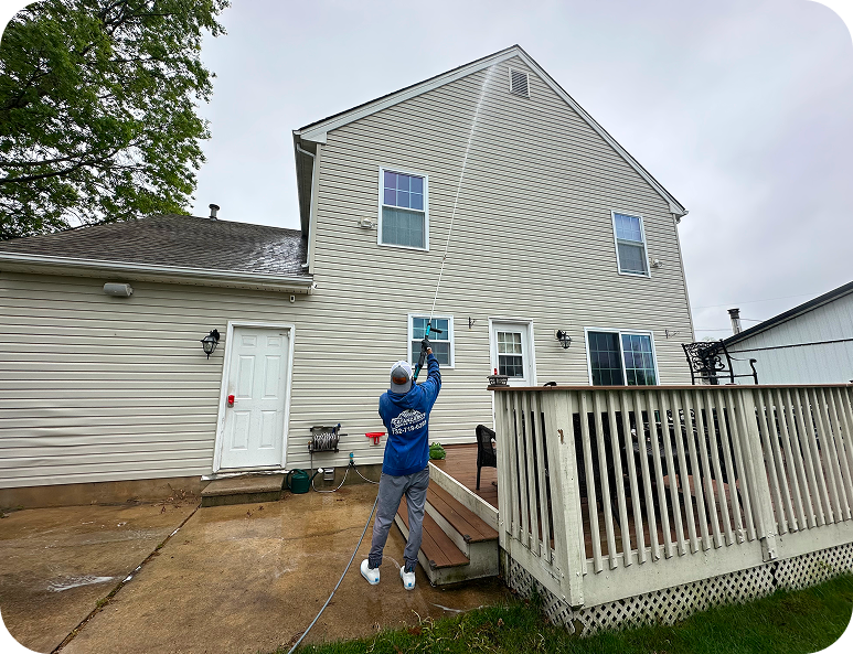 Person painting a house exterior with striped siding, standing on a ladder near a deck.
