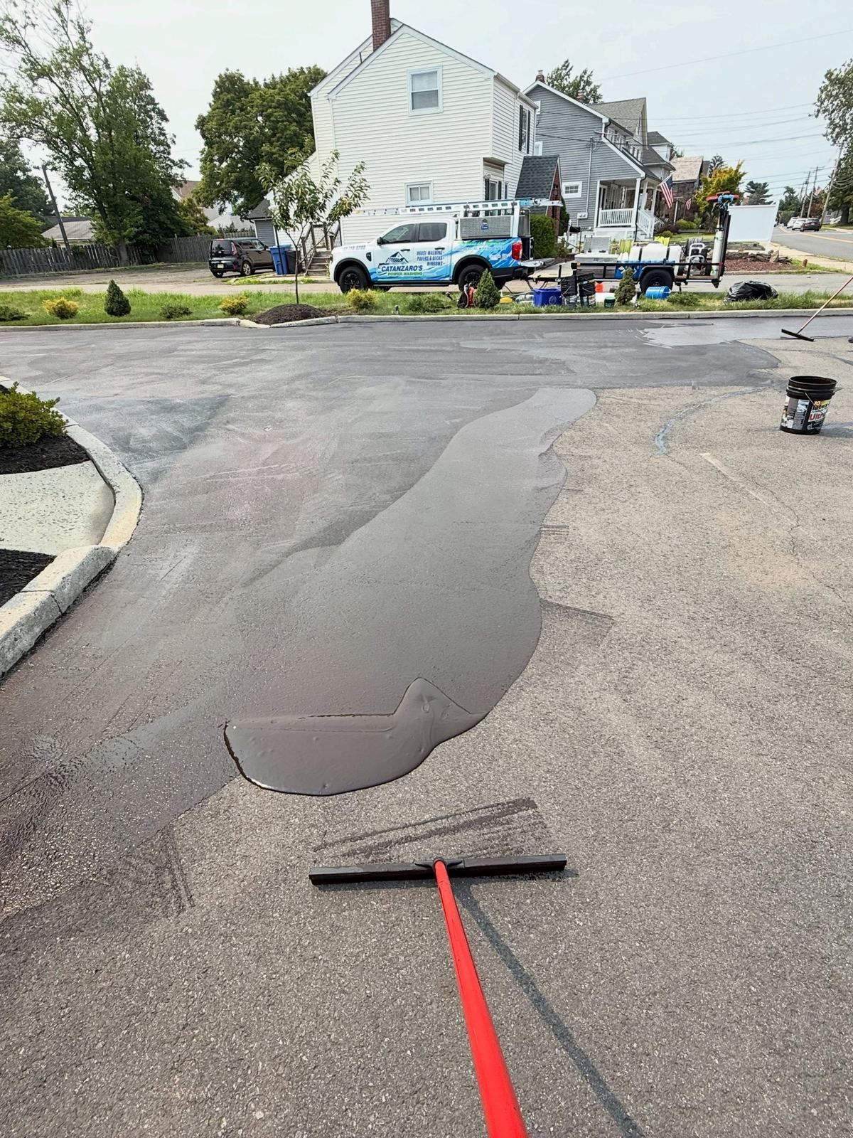 Parking lot asphalt being squeegeed with sealer — Catanzaro's Power Washing
