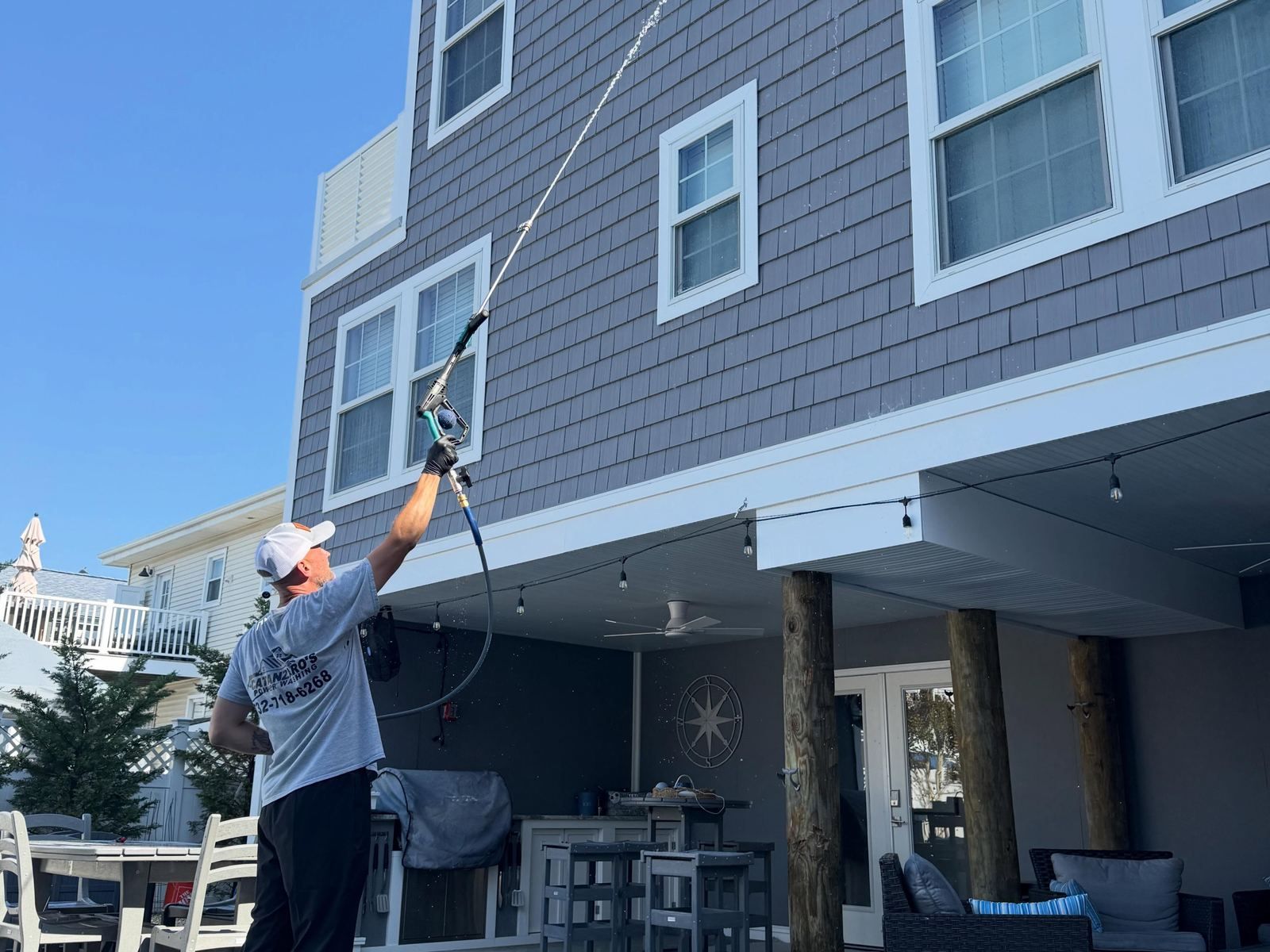 Crew soft washing shore house from below — Catanzaro's Power Washing