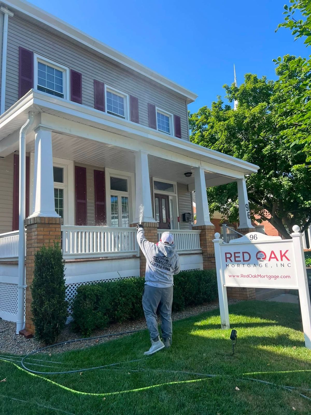 Crew washing porch house with sign — Catanzaro's Power Washing