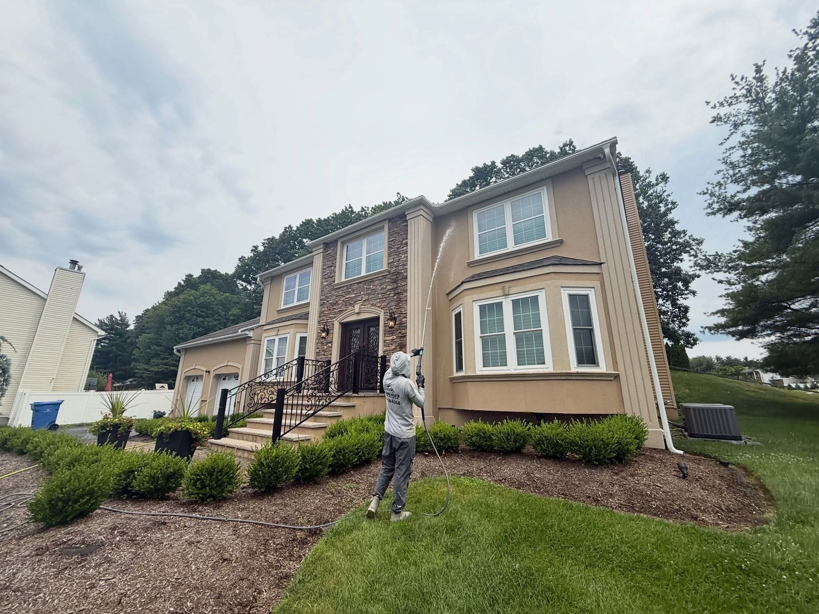Crew washing tan two-story front — Catanzaro's Power Washing