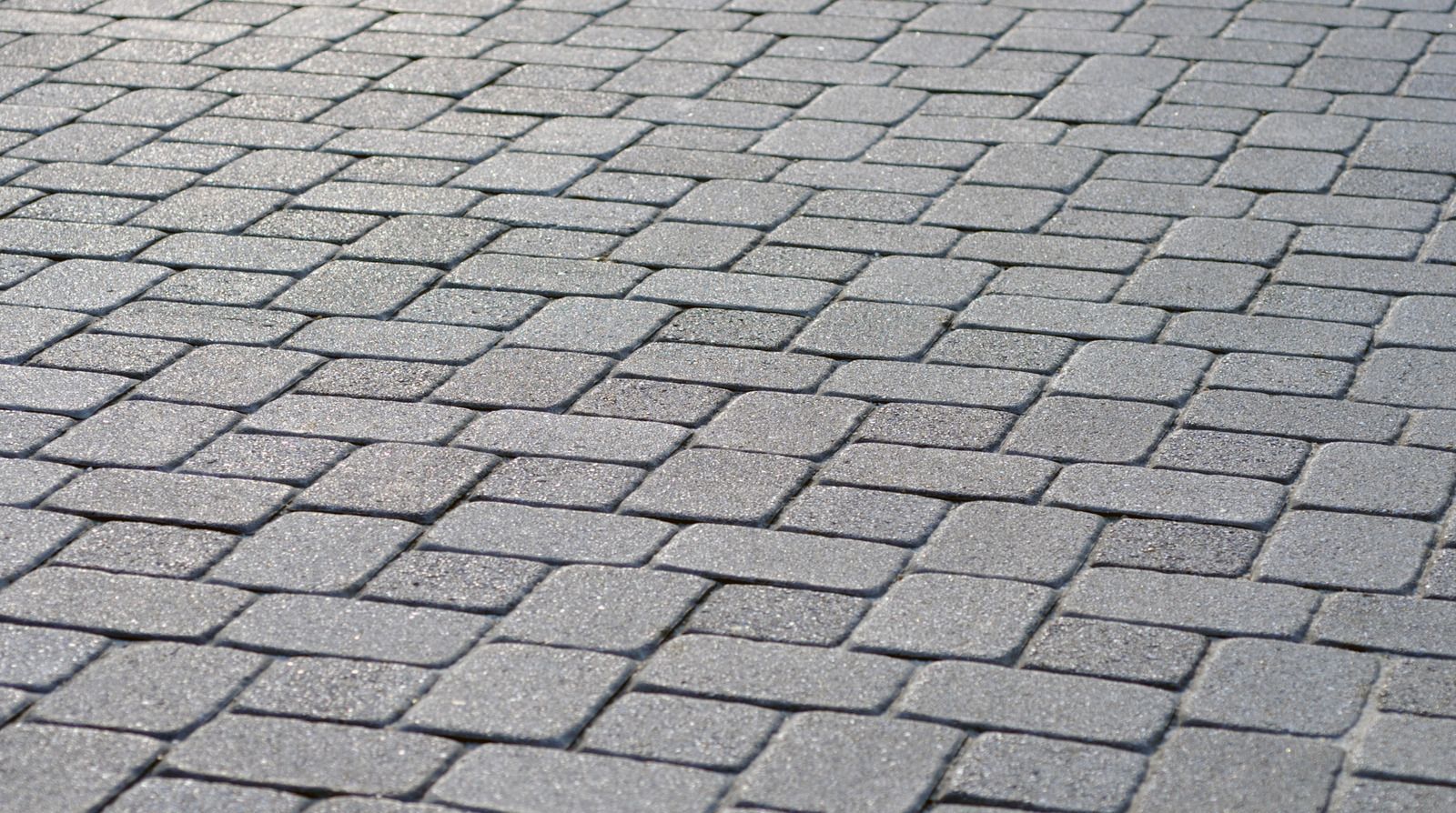Gray cobblestone pavement with a repeating brick pattern and no people or objects visible