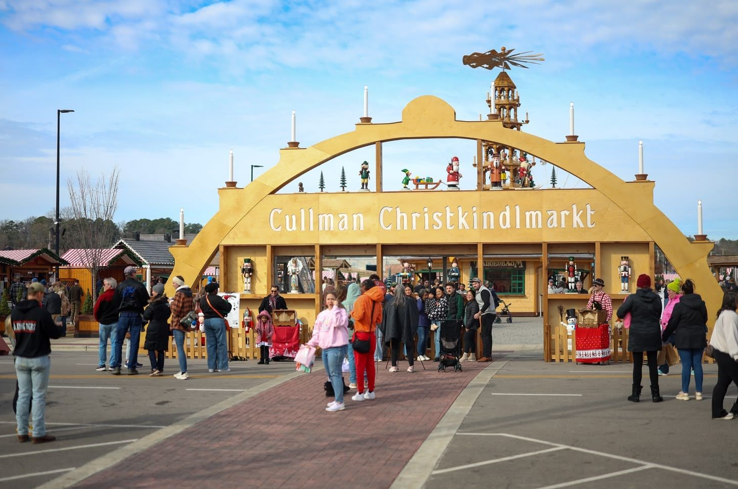Crowd gathered at the largest walk through Schwibbogen, the entrance of the Cullman Christkindlmarkt on a sunny day