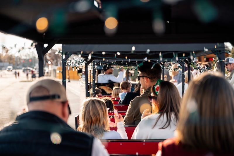 A little boy is riding a christmas train in the snow.