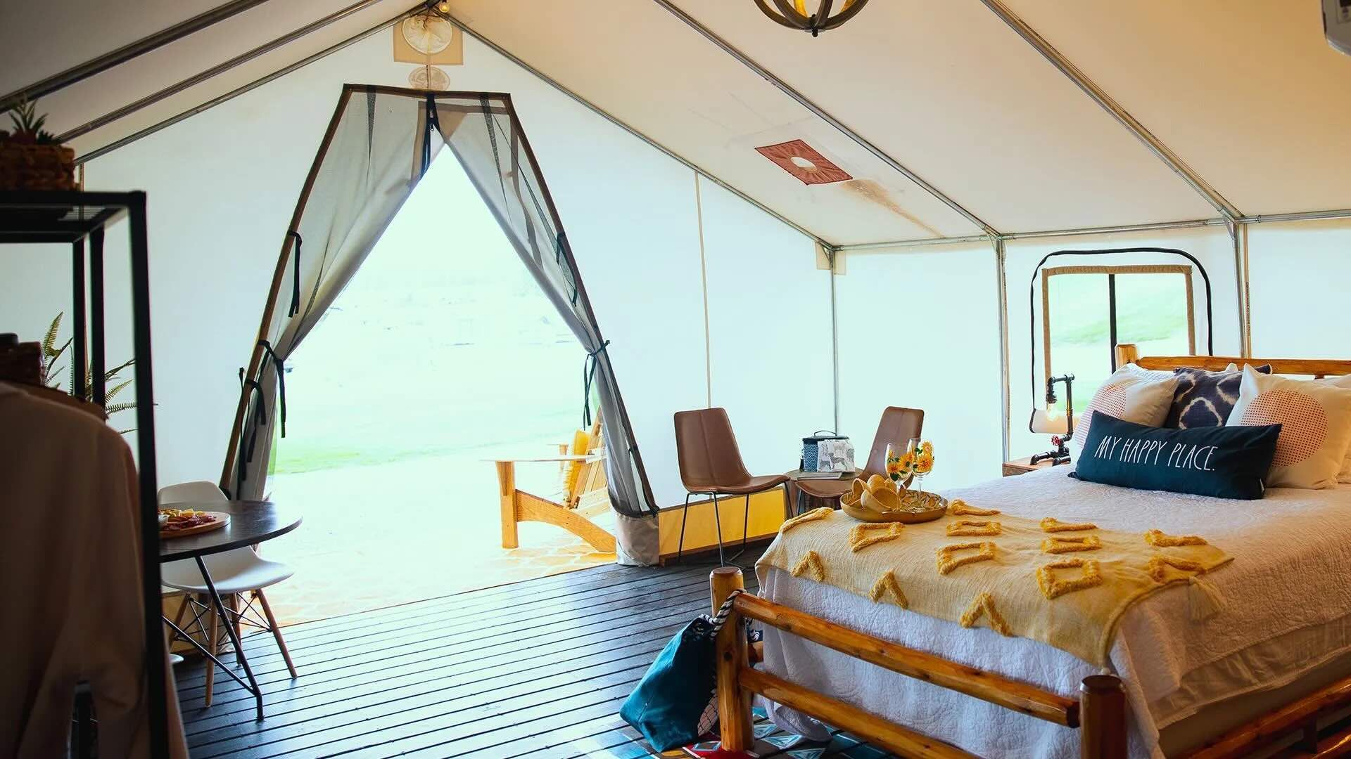 A large tent with a bed and chairs inside of it.