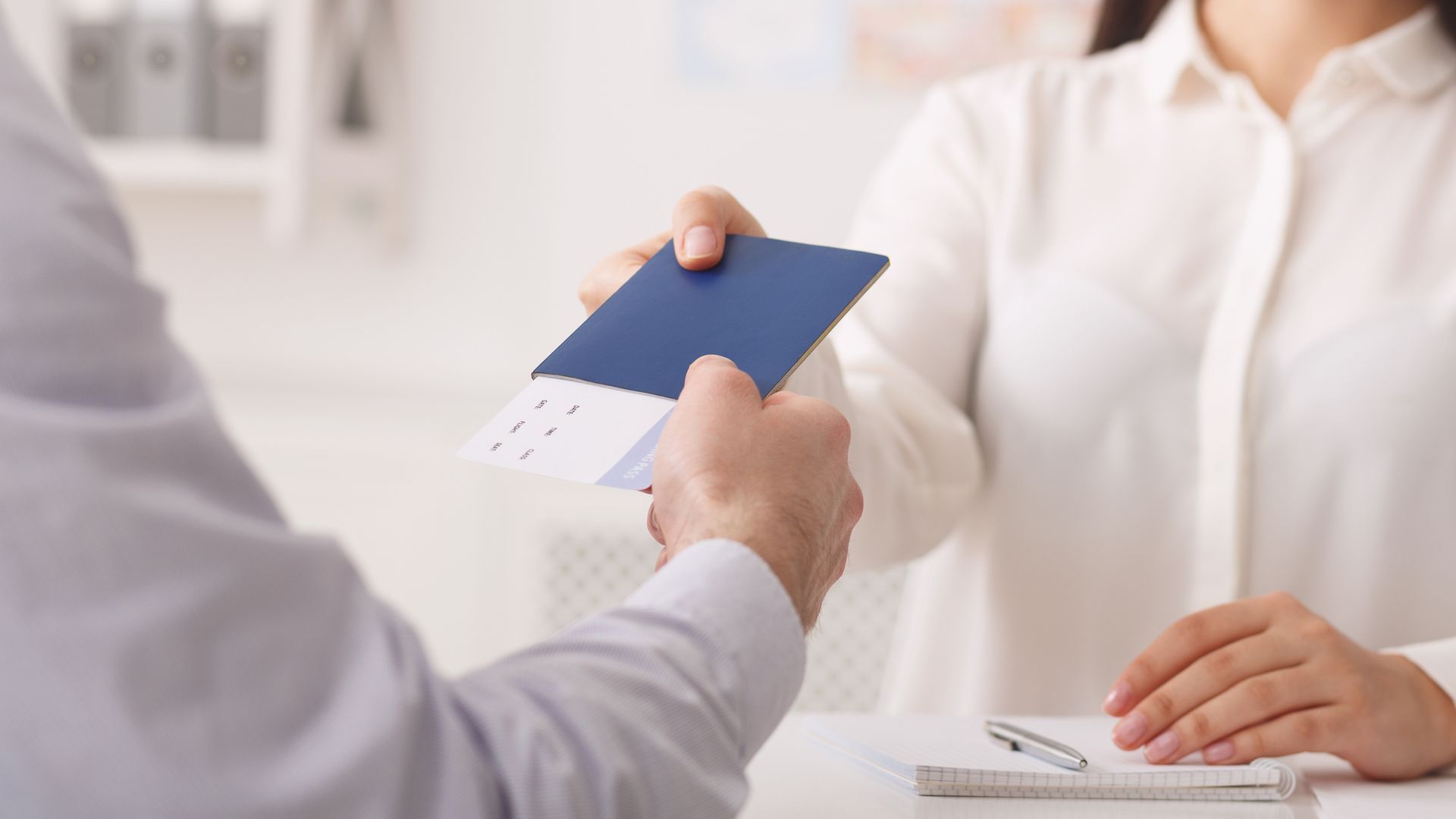 Un hombre le entrega un pasaporte a una mujer.