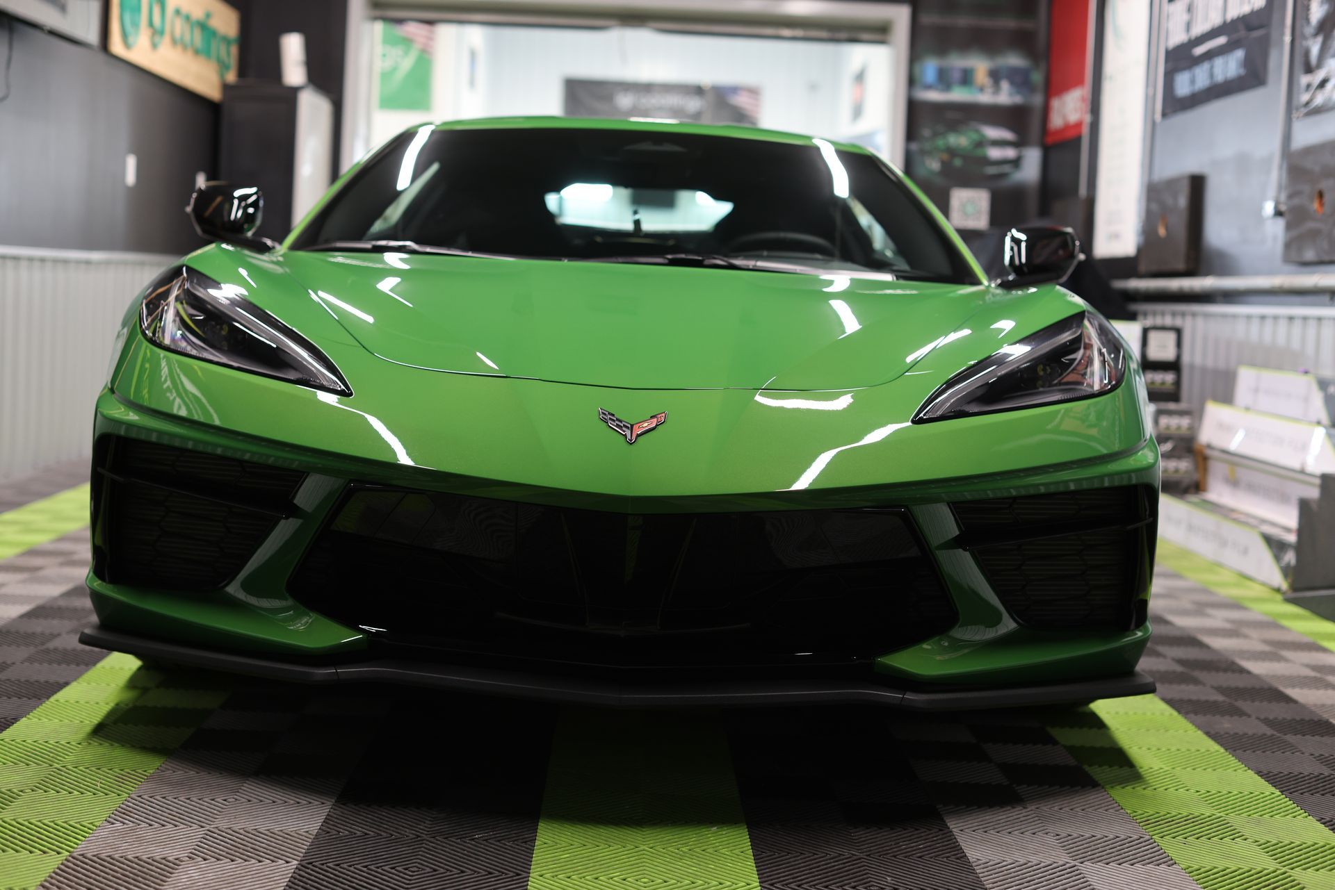 Bright green Chevrolet Corvette parked indoors on a checkered floor in a garage/detailing bay
