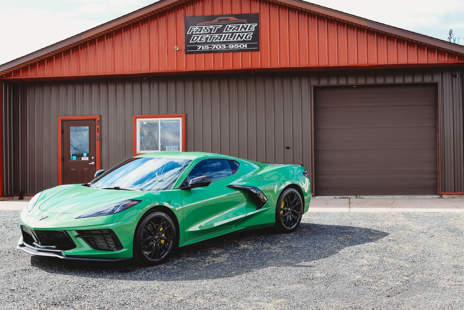 Green sports car parked in front of a brown building with a garage door