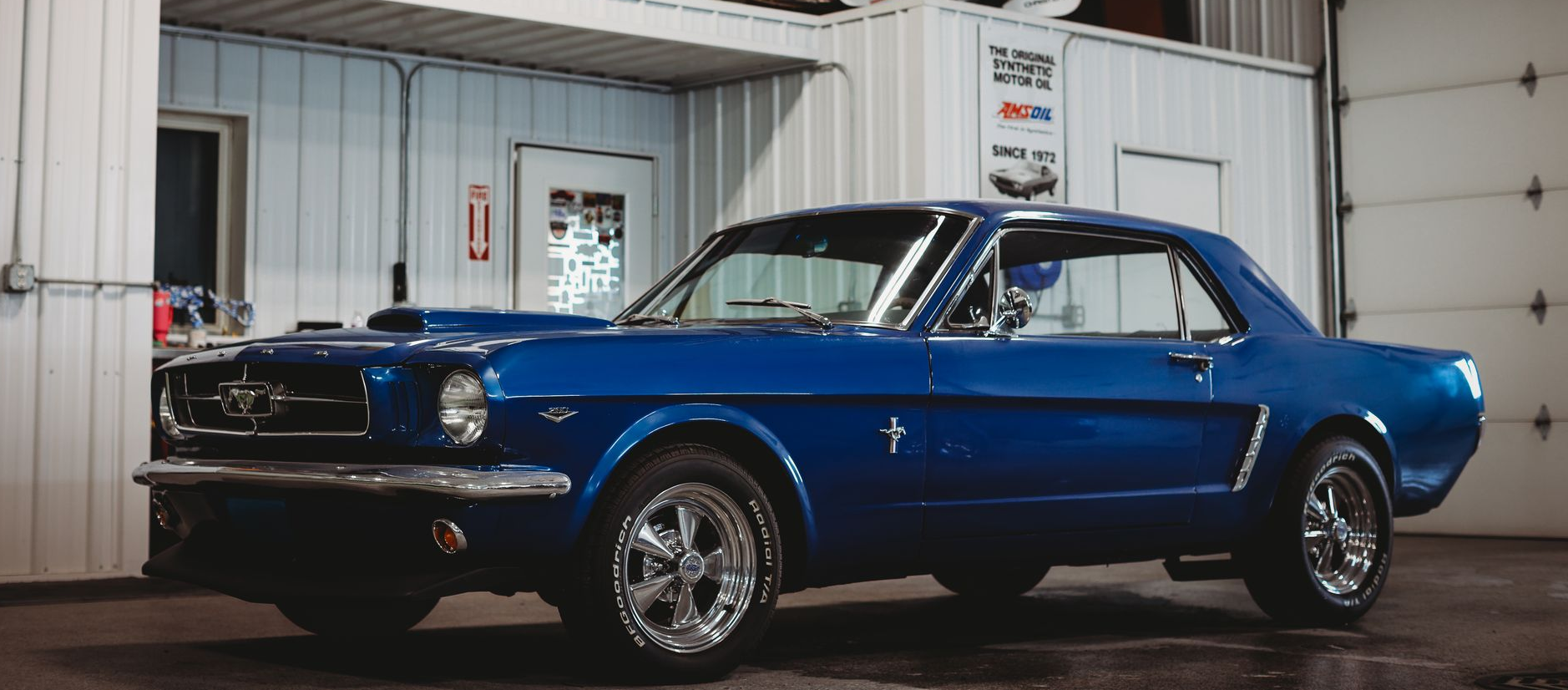 Blue classic car in a garage with racing signs and a checkered floor