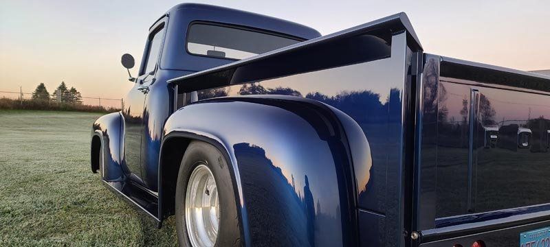 A blue truck is parked in a grassy field.