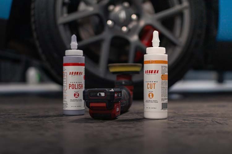Three bottles of polish are sitting next to a car wheel.