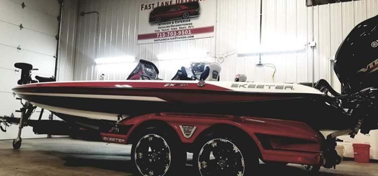 A red and white fishing boat is parked in a garage.