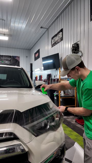 A person is cleaning a car with a blue sponge.